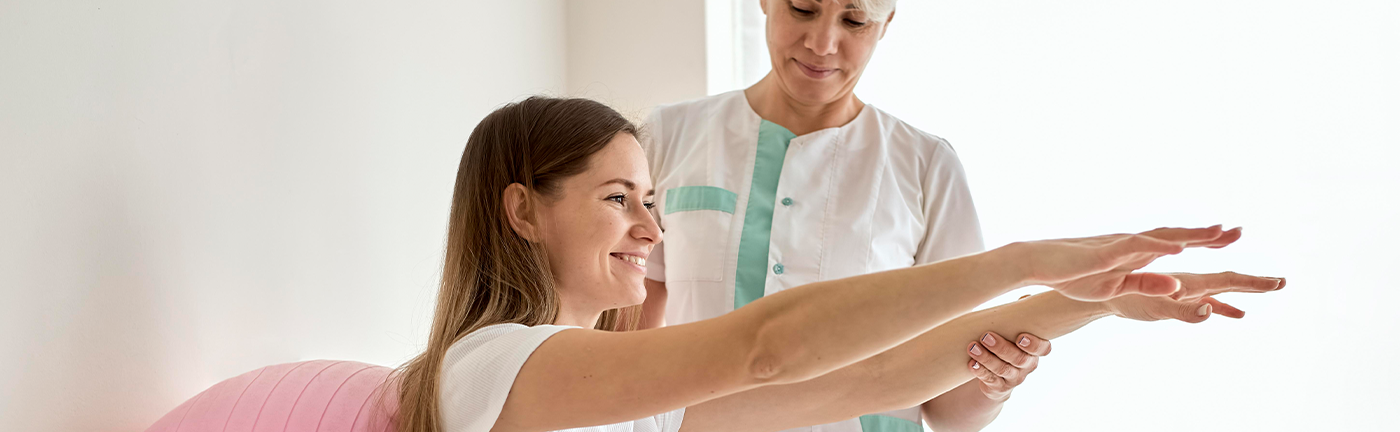 Therapist encouraging an elderly woman to perform arm stretching exercises