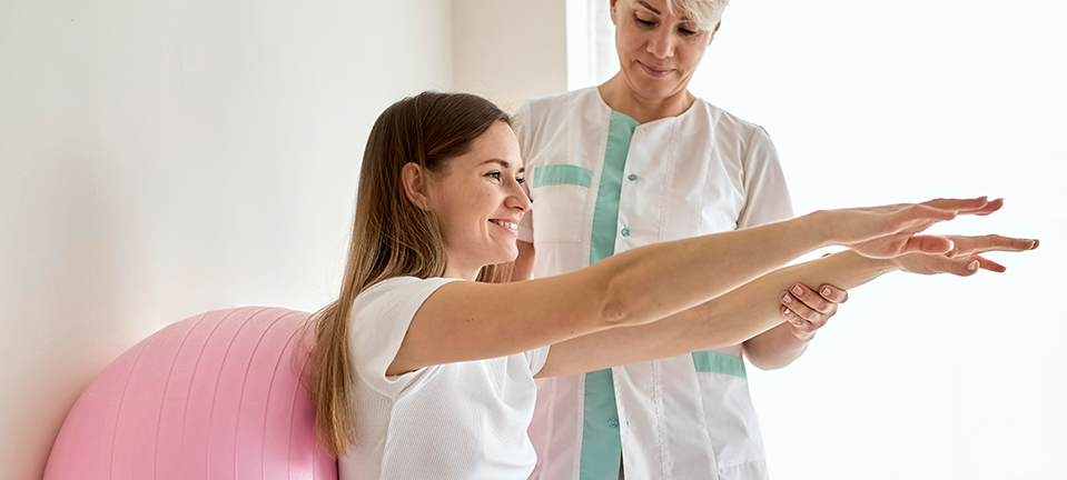 Therapist encouraging an elderly woman to perform arm stretching exercises