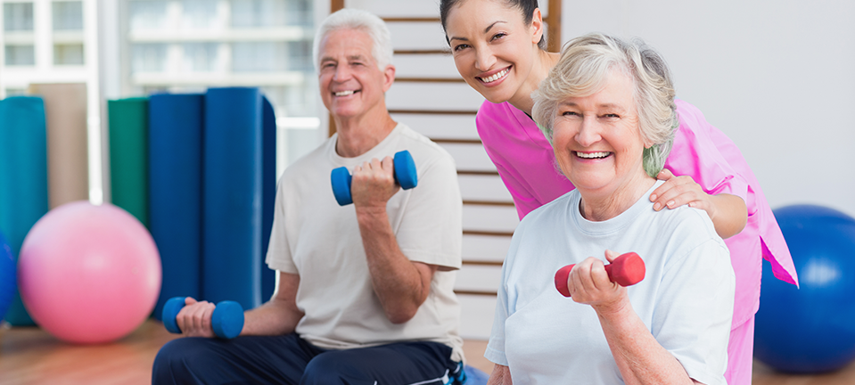 Therapist encouraging an elderly woman to perform arm stretching exercises