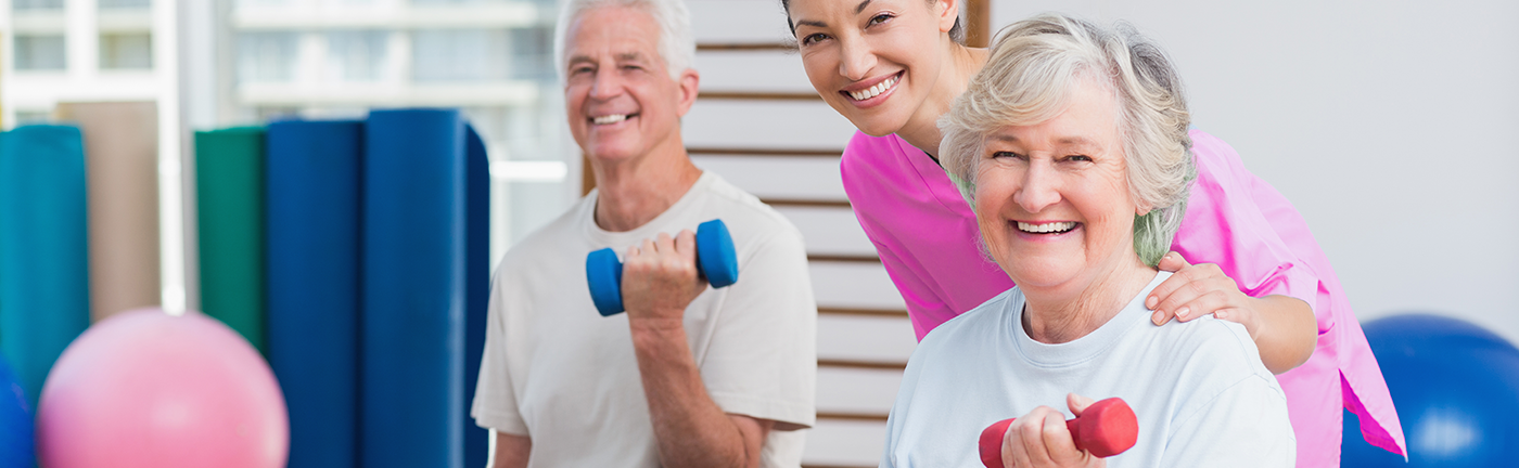 Therapist encouraging an elderly woman to perform arm stretching exercises